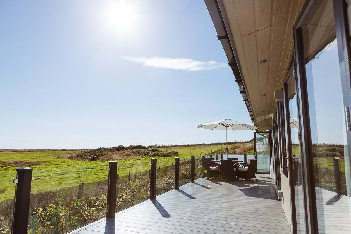 silver-bay-holiday-village-luxury-lodges-anglesey-headland-rise-shearwater-decking-table-sunshine.jpg