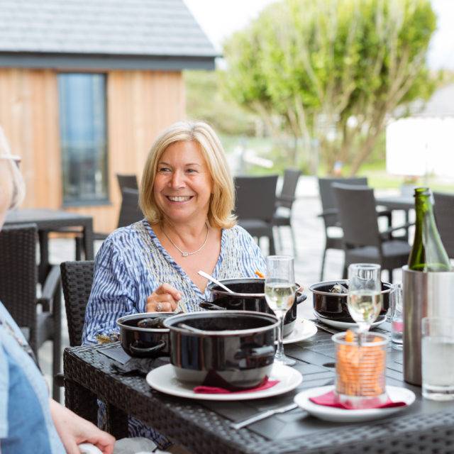 https://bulmerleisure.co.uk/wp-content/uploads/2016/12/silver-bay-holiday-village-anglesey-the-deck-house-women-dining-outdoors-640x640.jpg
