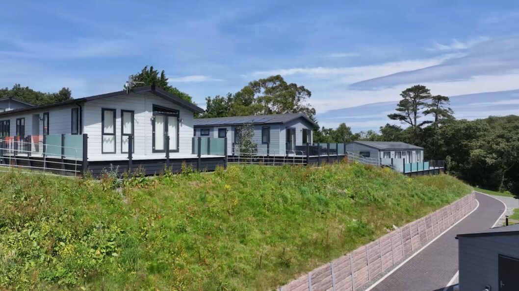 Lodges with glass-fronted decking on a grassy bank at Woodland Falls