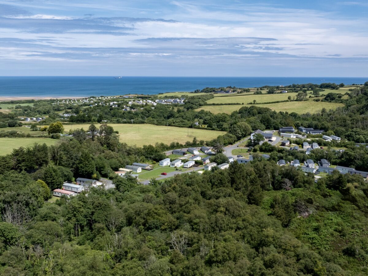 Woodland Falls holiday park from the air, set in woodland with Lligwy Bay beyond